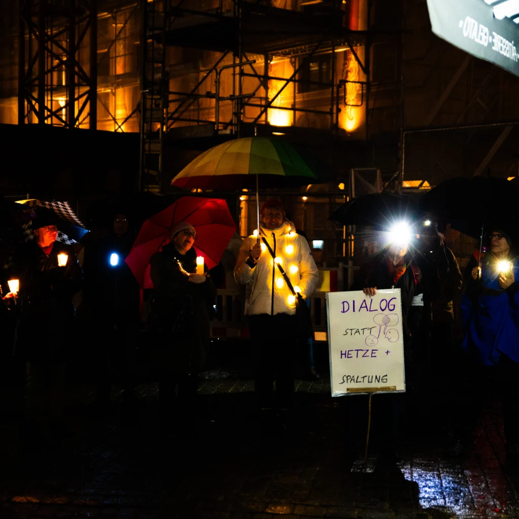 Kleine Gruppe von Menschen mit Regenschirm und Lichtern in der Hand